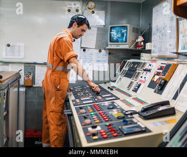 Ingegnere Marine officer avvia o arresta il motore principale della nave motore in sala di controllo ECR. I marinai di lavoro. Foto Stock