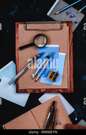 Appunti di legno con carta craft e schizzi su un posto di lavoro di designer di close-up. Bozzetti, bussole, righelli e matite a un architetto o interior d Foto Stock