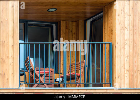 Il balcone di una casa in legno con sedie e un tavolo per il relax Foto Stock