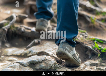 Il turista si inerpica su per la collina su pietre scivolose, gambe close-up Foto Stock