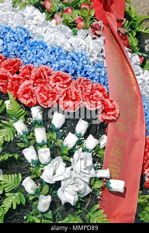 Una chiusura del rosso, del blu e del bianco fiori posti su un memoriale di guerra nelle regioni di Volgograd, Russia Foto Stock