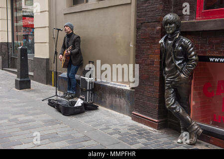 Suonatore ambulante accanto alla statua di John Lennon in Matthew Street, Liverpool Foto Stock