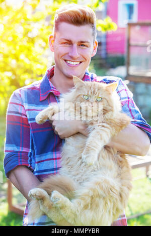 Ritratto di bella bionda uomo tenendo un Rosso tabby cat Foto Stock