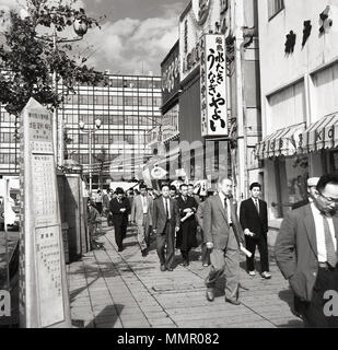 Degli anni Cinquanta, storico adatta Japaese gli uomini a camminare su un ampio marciapiede sul loro modo al loro posto di lavoro, Tokyo, Giappone. Foto Stock