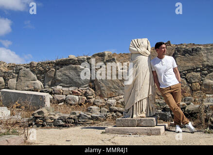 Bel giovane appoggiata contro la statua antica Foto Stock