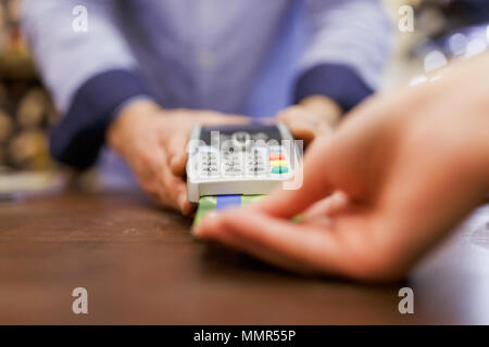 Immagine del venditore maschio con il terminale in mano e acquirente con la carta di credito. Sfondo sfocato. Foto Stock