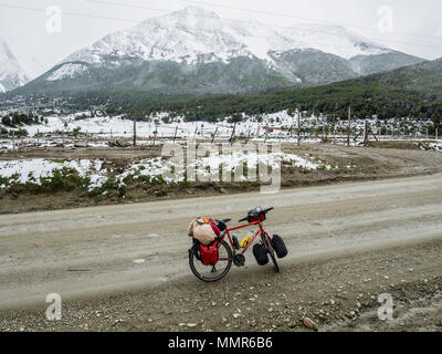 Bicicletta sulla strada vicino a Ushuaia, montagne coperte di neve, strada di ghiaia, Patagonia, Ushuaia, Argentina Foto Stock