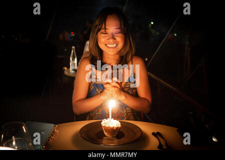 Giovane donna festeggia il suo compleanno e la realizzazione di un desiderio a cena in un bel ristorante Foto Stock