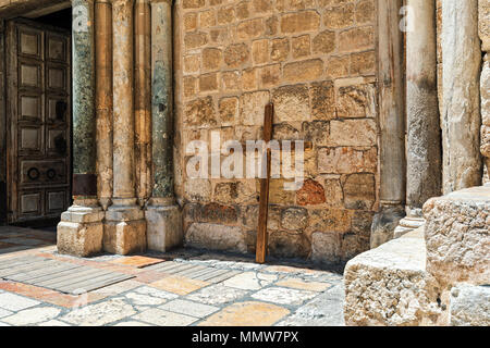 Grande Croce di legno in appoggio contro la parete di pietra della chiesa del Santo Sepolcro nella Città Vecchia di Gerusalemme, Israele. Foto Stock