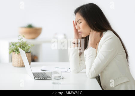 Sottolineato asian imprenditrice avente mal di testa o emicrania durante il lavoro Foto Stock