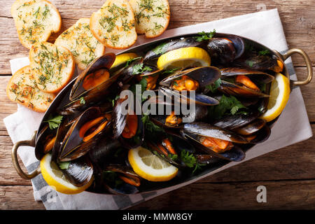 Cozze al vino con prezzemolo e limone. Frutti di mare. Le vongole in gusci. Deliziosi snack per i buongustai. parte superiore orizzontale vista da sopra, stile rustico Foto Stock