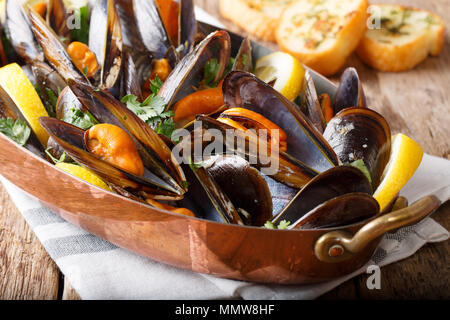 Cozze con limone e aglio macro in un tegame su una tavola orizzontale. Foto Stock