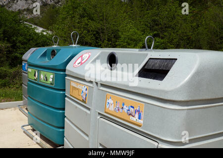 Colorate di grandi dimensioni cassonetti per il riciclaggio di carta vetro riciclaggio di imballaggi e contenitori in fila, allineati in Ariège, Francia, Foto Stock