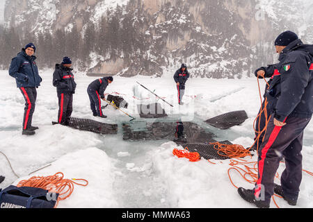 Lago di Braies, Italia - Marzo 10th, 2018: Italiani Carabinieri scavare un foro grande in profondità nel ghiaccio per consentire salvataggio divers entrando nel lago di Braies, Ita Foto Stock