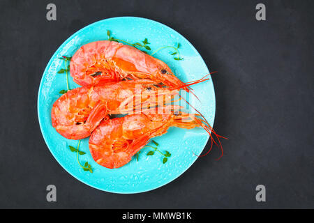 Grande royal materie gamberetti congelati su una piastra di colore blu con il timo e il basilico su una tabella di calcestruzzo. Il gambero rosso. Vista superiore Foto Stock