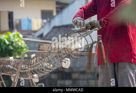 Lavoratori di mettere le mani sui guanti utilizzando la mano per filo di ferro per legare per la struttura della casa o edificio. Foto Stock