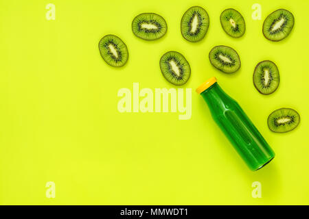Bella arte cibo sfondo. Succo verde in bottiglie di vetro tagliato a fette il kiwi sul verde brillante superficie. Foto Stock