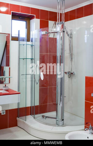 Interno di un bagno moderno. Interno in toni di rosso. Vetro cabina doccia. Foto Stock