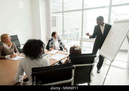 African business coach fornisce la presentazione per il team a bordo di soddisfare Foto Stock