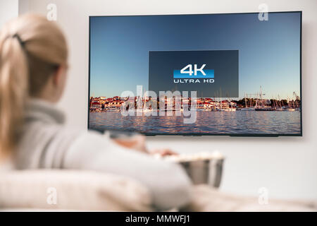 Grande e moderna TV con 4k risoluzioni e giovane donna in primo piano a guardare alcuni video Foto Stock