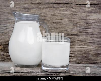Latte in vetreria su tavola in legno rustico Foto Stock