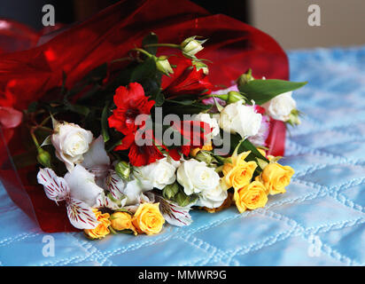 Un lussuoso bouquet di fiori si trova su un copriletto blu. Sorpresa al festival e in una data comune. Foto Stock