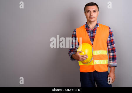 L'uomo lavoratore edile contro uno sfondo grigio Foto Stock