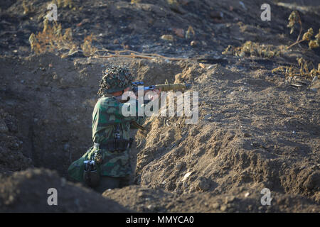 RYAZHENOE, AREA Taganrog, Russia, 20 AGOSTO 2017: cecchino soldier indossando un camuffamento uniforme è in piedi in una trincea di terracotta Foto Stock