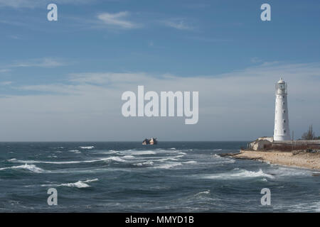 Il faro sul mare con la nave affondata Foto Stock