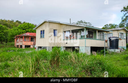 Antigua Piccole Antille isole dei Caraibi West Indies - donna siede sulla veranda a tipiche case sul ciglio della strada e baracche Foto Stock