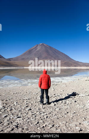 Giovane uomo che guarda alla Laguna Verde lago e Vulcano Licancabur in Reserva Nacional de fauna Andina Eduardo Avaroa in Bolivia Foto Stock