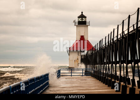 Un piccolo faro su un molo di San Joeseph Michigan durante stromy meteo con onde che si infrangono nel molo. Foto Stock