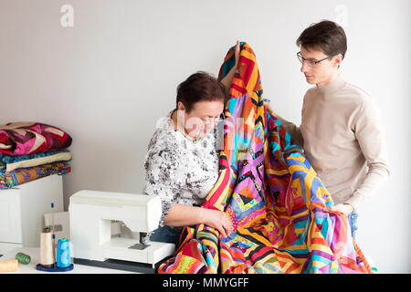 La trapuntatura, imbarcazioni, attrezzature concetto. nella cucitura di studio vi è un giovane uomo e di una donna anziana, essi detengono manto colorato fatto da mani in Foto Stock