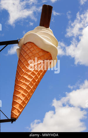 Plastica gigante cono gelato al di fuori di una gelateria contro un Cielo di estate blu Foto Stock