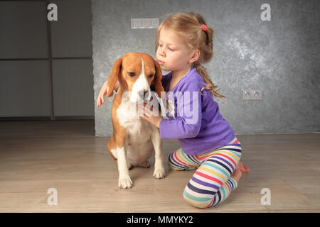 Bambina e cane sono il migliore amico. La ragazza che abbraccia il suo cane beagle vista da vicino. Foto Stock