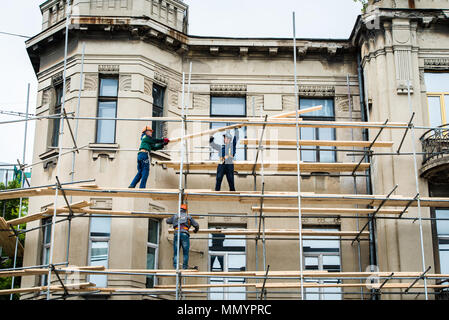 VLADIVOSTOK, RUSSIA - Giugno 14, 2016: lavoratori edili in impalcature sulla facciata del palazzo di ripristino, di riparazione e di rinnovamento. Foto Stock