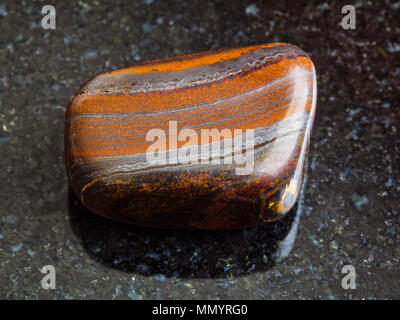 Le riprese in modalità macro di roccia naturale campione - burattati Jaspillite (Jaspilite, Taconite Jasper) pietra in granito nero lo sfondo da Australia Foto Stock