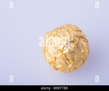 Il cioccolato a sfera o sfera di cioccolato con mandorle in oro una carta stagnola sullo sfondo Foto Stock