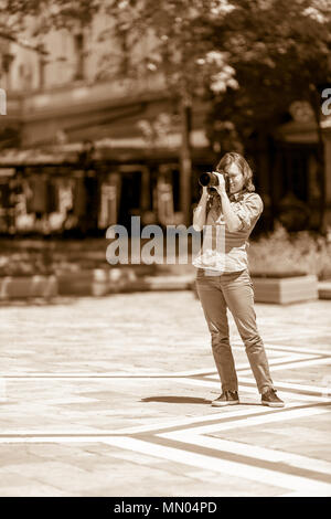 DIMITROVGRAD, Bulgaria - 30 Aprile 2018: bellissima femmina fotografo scatta foto con la sua big black fotocamera reflex digitale sotto il sole a street vigilia di concerto Foto Stock