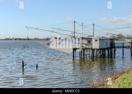 Tutina in rete appesa al vecchio tradizionale stilt Capanna di pesca sulla laguna salmastra, girato in primavera luminoso della luce del sole a Comacchio, Ferrara, Italia Foto Stock