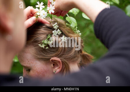 Una giovane ragazza ha fiori di primavera collocato nel suo capelli intrecciati Foto Stock