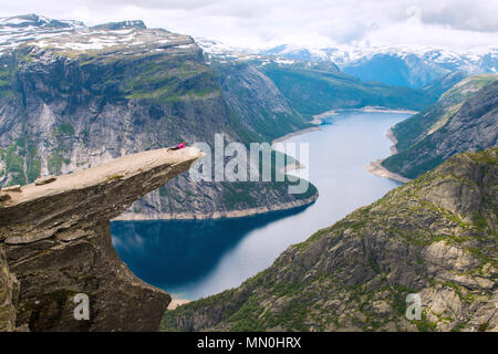 Sportivo da donna in posa sul Trolltunga. Felice escursionista godere del bellissimo lago e buone condizioni meteorologiche in Norvegia. Foto Stock