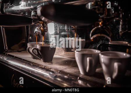Macchina per caffè preparare caffè fresco e versare in bicchieri di bianco al ristorante, bar o pub Foto Stock
