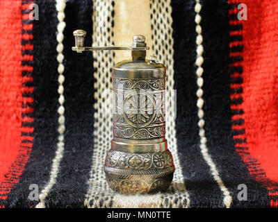 Turco mano vintage macinino spice, alternativamente chiamati pepe turco mill, su di un antico canto-tessuto. Foto Stock