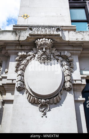 Frame ovale circondato da ghirlande di fiori e nastri con una scultura di testa che decorano la facciata di dal grande magazzino Selfridges, London, Regno Unito Foto Stock