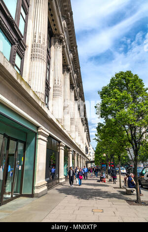 Le persone camminare per Oxford Street accanto alla facciata anteriore iconica dal grande magazzino Selfridges, London, Regno Unito Foto Stock