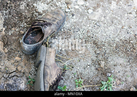 Coppia di old dirty scarpe usate. Abbandonato scartato stivali posa in polvere sul terreno. La povertà o beggary concetto. Copyspace Foto Stock