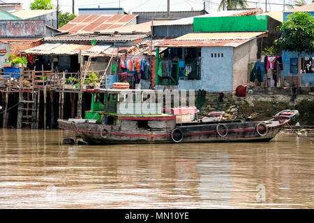 Case in legno e una barca lungo il fiume Mekong in Vietnam del Sud in una giornata di sole. Foto Stock