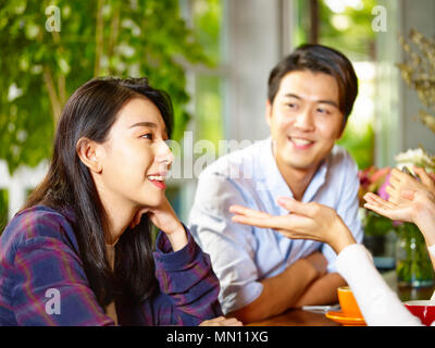 Felice giovane coppia asiatica in conversazione con gli amici in un coffee shop Foto Stock