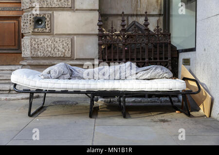 Una traversina ruvida del luogo di riposo per la notte nella forma di un campeggio Bed con materasso e coperta sul marciapiede sulla Piccadilly nel centro di Londra. Il fenomeno dei senzatetto è diventato un più visibile il problema ancora una volta a Londra negli ultimi mesi e ci sono stati tentativi controversi per rimuovere le traversine ruvida dalle strade sia a Londra e Windsor nelle settimane di funzionamento fino al Royal Wedding. Credito: Imageplotter News e sport/Alamy Live News Foto Stock